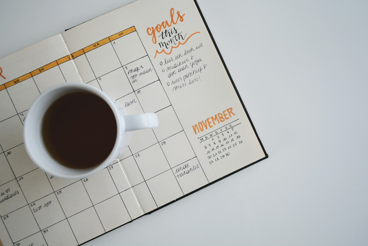 Ein aufgeschlagener Papierplaner mit einer Tasse Kaffee, der an Terminplanung und Buchungen denken lässt